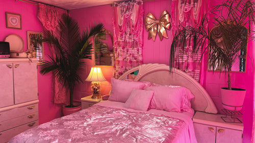 A bold 80s–90s pink bedroom set with lacquer furniture, mirror headboard, palm trees, and vintage decor. Perfect for fashion, beauty, and GRWM content.